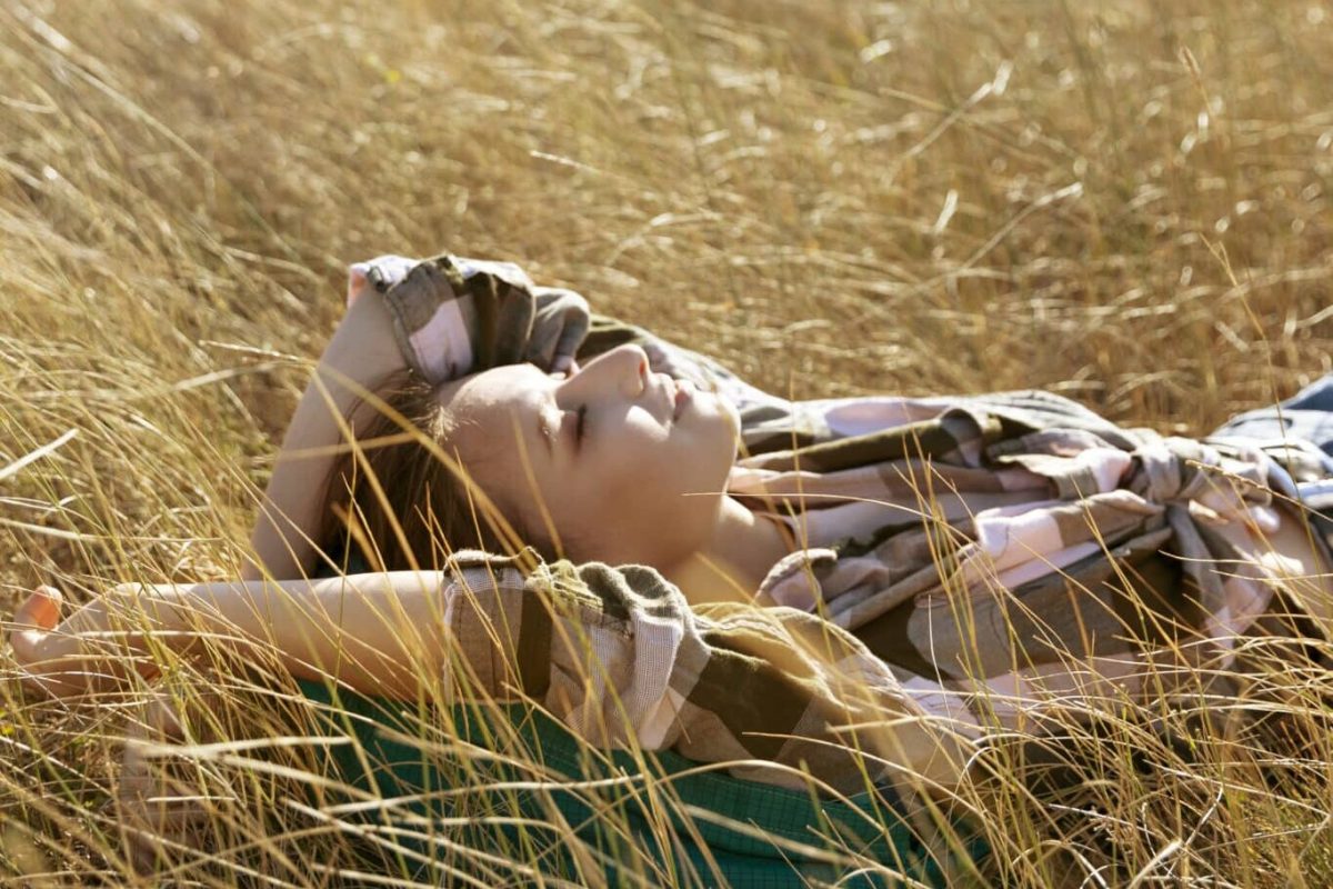 young woman reflecting deeper states of higher consciousness laying in a field